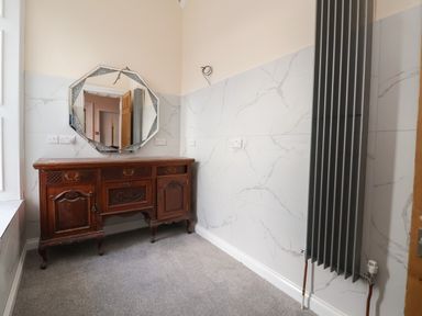 A room with a wooden cabinet a wall mirror and a tall radiator at The Lloyd George in Bontnewydd Gwynedd