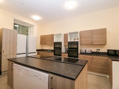 A kitchen with wooden cabinets black countertops double ovens dishwashers and white refrigerators at The Lloyd George in Bontnewydd Gwynedd