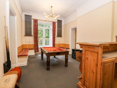 A games room with a pool table a wooden bar built in benches and large windows at The Lloyd George in Bontnewydd Gwynedd