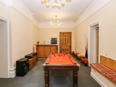 A room with a pool table chairs a wooden bar and speakers at The Lloyd George in Bontnewydd Gwynedd