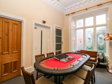 A poker table with chips and chairs around it next to a wooden door and decorative windows at The Lloyd George in Bontnewydd Gwynedd