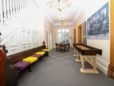 A hallway with a wooden bench with cushions a shuffleboard table a dining table and chairs at The Lloyd George in Bontnewydd Gwynedd