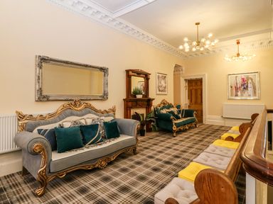 A sitting room with two ornate sofas a fireplace a large wall mirror and cushioned wooden bench seating at The Lloyd George in Bontnewydd Gwynedd