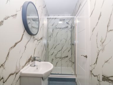 A bathroom with a sink and mirror opposite a shower enclosure with sliding doors at The Lloyd George in Bontnewydd Gwynedd