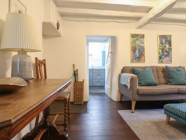 A living room with a wooden table lamp and chairs a gray sofa with blue pillows and two framed pictures on the wall at 3 Ivy Court in Dolgellau