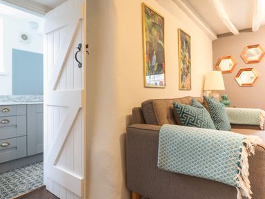 A living room with brown sofas blue patterned cushions and throws and a view into a kitchen at 3 Ivy Court in Dolgellau