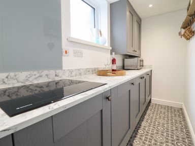 A kitchen with grey cabinets patterned floor and a marble countertop at 3 Ivy Court in Dolgellau