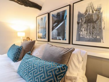 A bed with patterned blue and plain grey pillows and three framed artworks above at 3 Ivy Court in Dolgellau