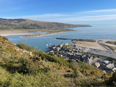 A coastal town with boats in a harbor and hills in the background at Deu-Ddrws in Barmouth