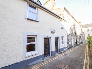 Exterior of stone and stucco houses with windows and doors on a narrow street at Deu-Ddrws in Barmouth