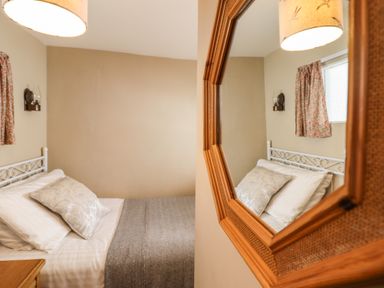 A bedroom with a bed pillow blanket and mirror on the wall at Deu-Ddrws in Barmouth