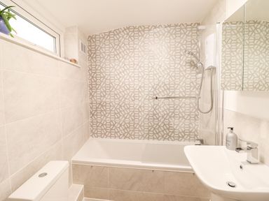 A bathroom with a bathtub shower combination a toilet and a sink at Deu-Ddrws in Barmouth