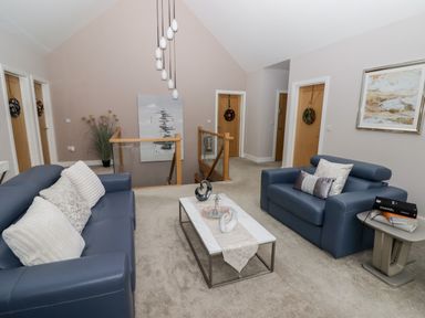 A seating area with two blue sofas a coffee table with decorative items and a side table with books at Ty Marlyn in Crofty