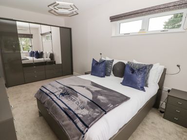 A bedroom with a bed with pillows and a blanket a wardrobe with mirrored doors and a bedside table at Ty Marlyn in Crofty