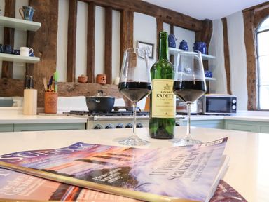 A kitchen with wine glasses and a bottle on a countertop and magazines nearby at The Bridewell in Woodbridge