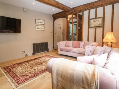 A living room with two sofas a rug a wall mounted television and wooden beams at The Bridewell in Woodbridge