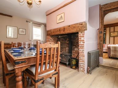 A dining room with a wooden table and chairs next to a brick fireplace at The Bridewell in Woodbridge