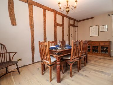 A dining room with a wooden table and six chairs beside exposed wooden beam walls at The Bridewell in Woodbridge