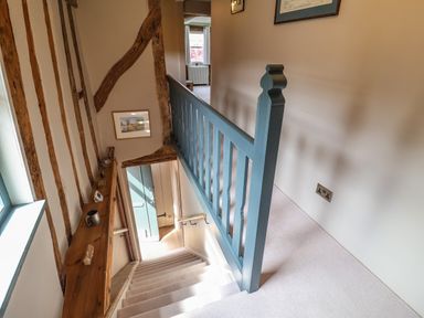 A staircase with blue wooden railing and wooden beams on the wall at The Bridewell in Woodbridge