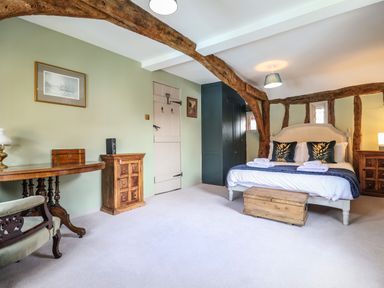A bedroom with exposed wooden beams a bed with pillows and folded towels wooden furniture and a green painted wall at The Bridewell in Woodbridge