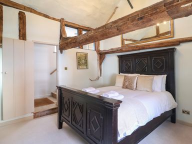 A bedroom with a wooden bed frame pillows and exposed ceiling beams at The Bridewell in Woodbridge