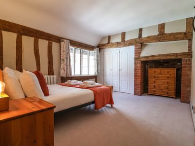 A bedroom with a bed bedside table window chest of drawers and built in wardrobes at The Bridewell in Woodbridge