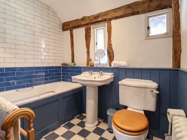 A bathroom with a bathtub sink and toilet with wooden beams on the wall at The Bridewell in Woodbridge