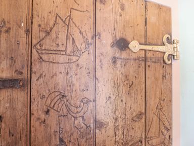 A wooden door with carvings of a ship and a bird at The Bridewell in Woodbridge