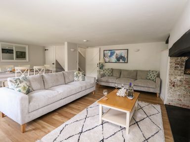 A living room with two sofas a wooden coffee table and a dining table at Dairy Cottage in Abbotsbury