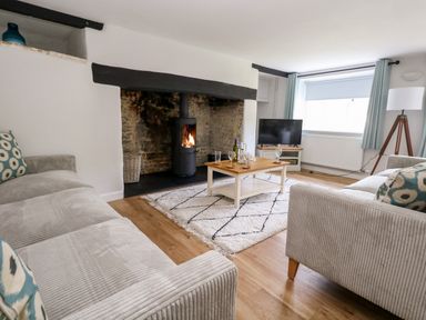 A living room with two sofas a coffee table and a fireplace at Dairy Cottage in Abbotsbury