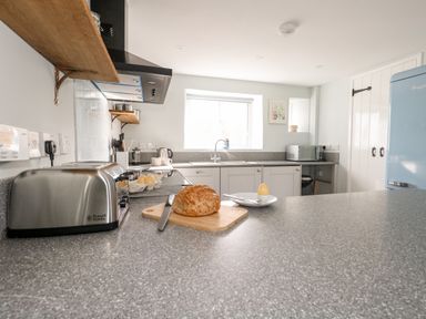 A kitchen with a toaster bread and egg on the counter near a window at Dairy Cottage in Abbotsbury