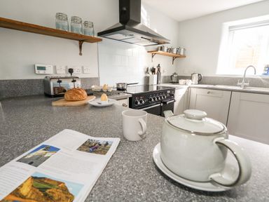 A kitchen with countertop utensils stove and a teapot at Dairy Cottage in Abbotsbury