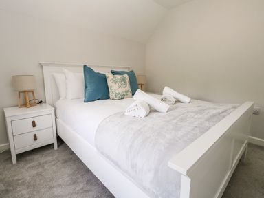A bedroom with a white bed and bedside tables with lamps at Dairy Cottage in Abbotsbury