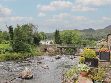 A river with a bridge surrounded by greenery at Riverside Cottage Beddgelert