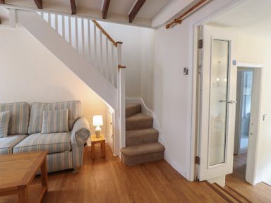 A living room with a sofa and stairs at Riverside Cottage in Beddgelert