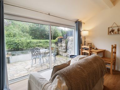 A living room with a view of the garden at Riverside Cottage in Beddgelert