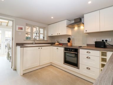 A kitchen with white cabinets oven stovetop sink and a toaster at 2 Mosses Cottage in Friston