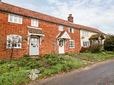 A row of brick cottages with tiled roofs and small gardens in front at 2 Mosses Cottage in Friston