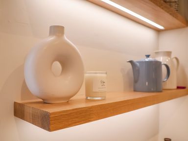 A wooden wall shelf with a white circular vase candle blue teapot and white jug at The Middle House in Southwold