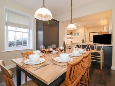 A dining area with a wooden table set with bowls plates glasses and wine glasses at The Middle House in Southwold