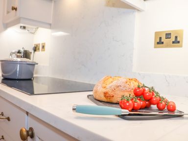 A kitchen countertop with a loaf of bread and tomatoes on a cutting board at The Middle House in Southwold