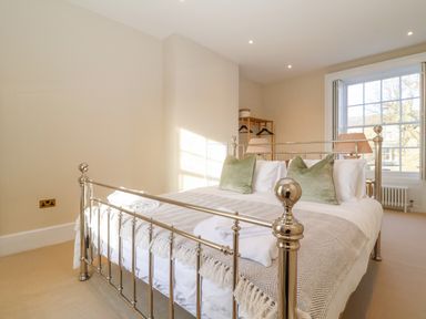 A bedroom with a metal bed frame pillows and a window at The Middle House in Southwold