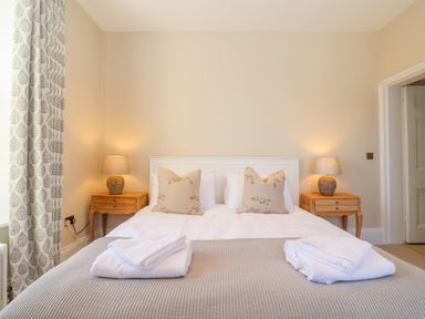 A bedroom with a double bed two bedside tables with lamps and folded towels at The Middle House in Southwold
