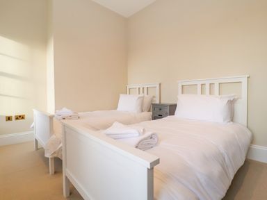 A bedroom with two single beds and a small grey nightstand between them at The Middle House in Southwold