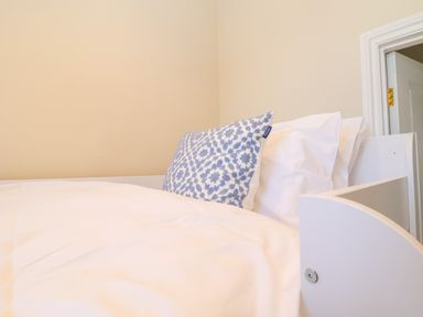A bed with white bedding and a blue and white patterned pillow in a room at The Middle House in Southwold