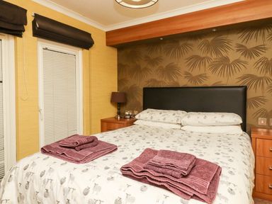 A bedroom with a bed with folded towels bedside tables and a lamp at Washburn Lodge in Fewston near Darley