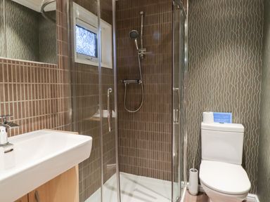 A bathroom with a shower area with glass doors a white toilet and a sink at Washburn Lodge in Fewston near Darley