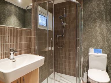 A bathroom with a sink wooden cabinet shower enclosure with glass doors and a toilet at Washburn Lodge in Fewston near Darley