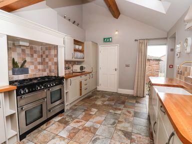 A kitchen with tiled floor wooden countertops double oven stove and door leading outside at The Stables and West Wing in Bolton Percy near Tadcaster