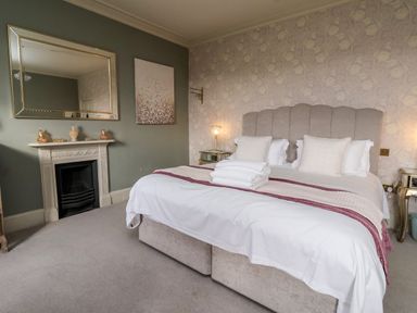 A bedroom with a large bed towels on bed a fireplace and mirror on wall at The Stables and West Wing Bolton Percy near Tadcaster